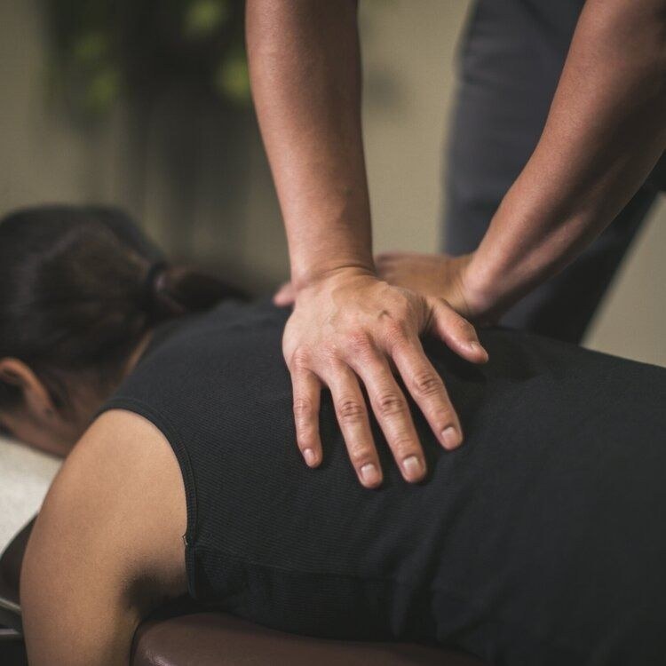 Hands working along a patient's mid-back during a chiropractic adjustment